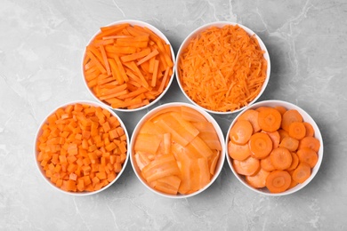 Photo of Flat lay composition with bowls of differently cut carrots on marble background