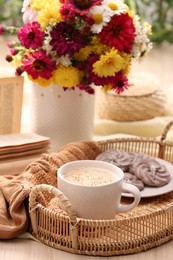 Photo of Cup of hot coffee, delicious cookies and beautiful bouquet on wooden table