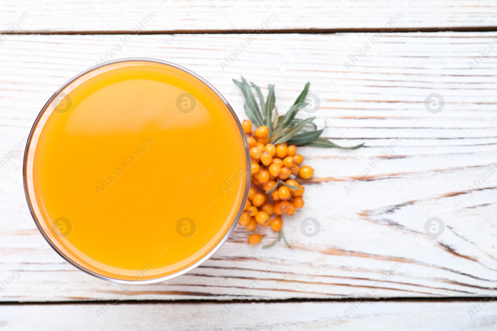 Photo of Delicious sea buckthorn juice and fresh berries on white wooden table, top view. Space for text