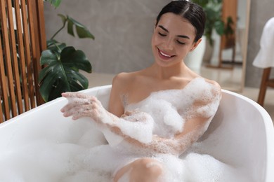 Photo of Beautiful young woman taking bubble bath at home