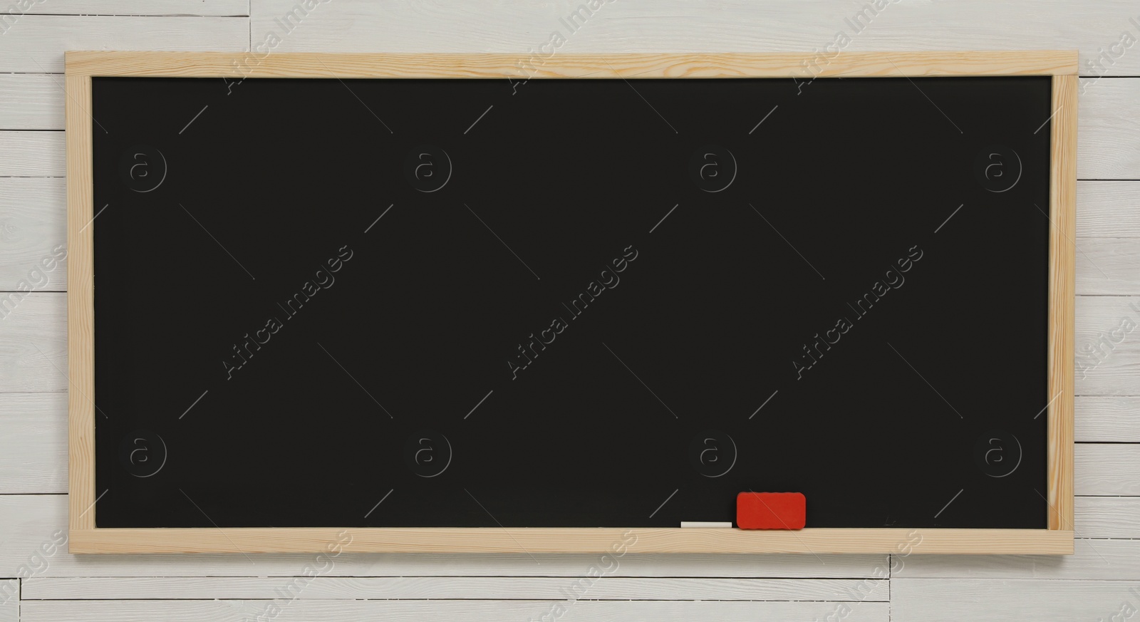 Photo of Clean black chalkboard hanging on white wooden wall