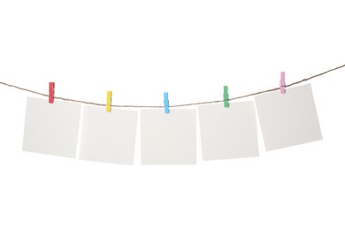 Photo of Clothespins with empty notepapers on string against white background. Space for text