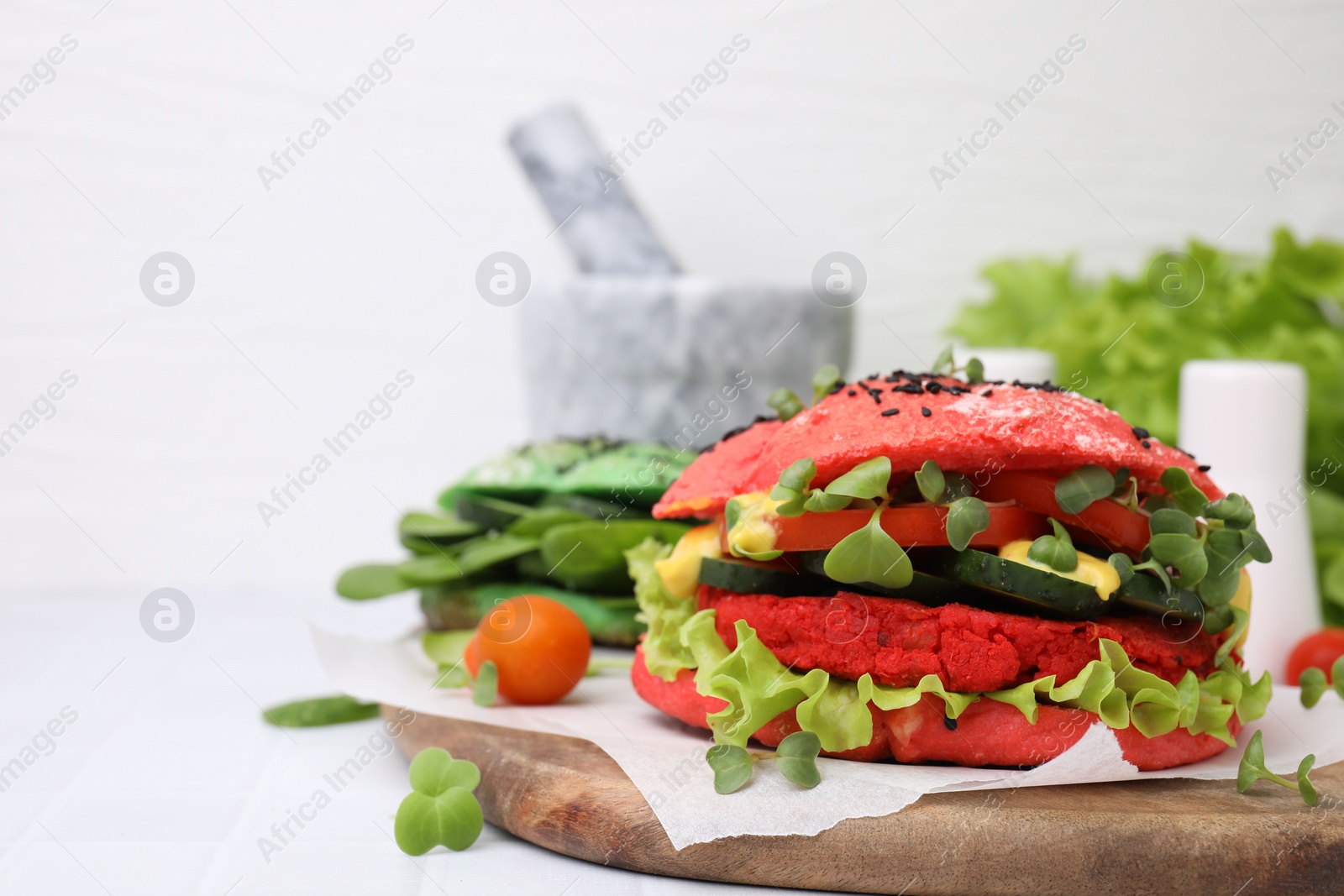 Photo of Tasty pink vegan burger with vegetables, patty and microgreens on white tiled table, closeup. Space for text