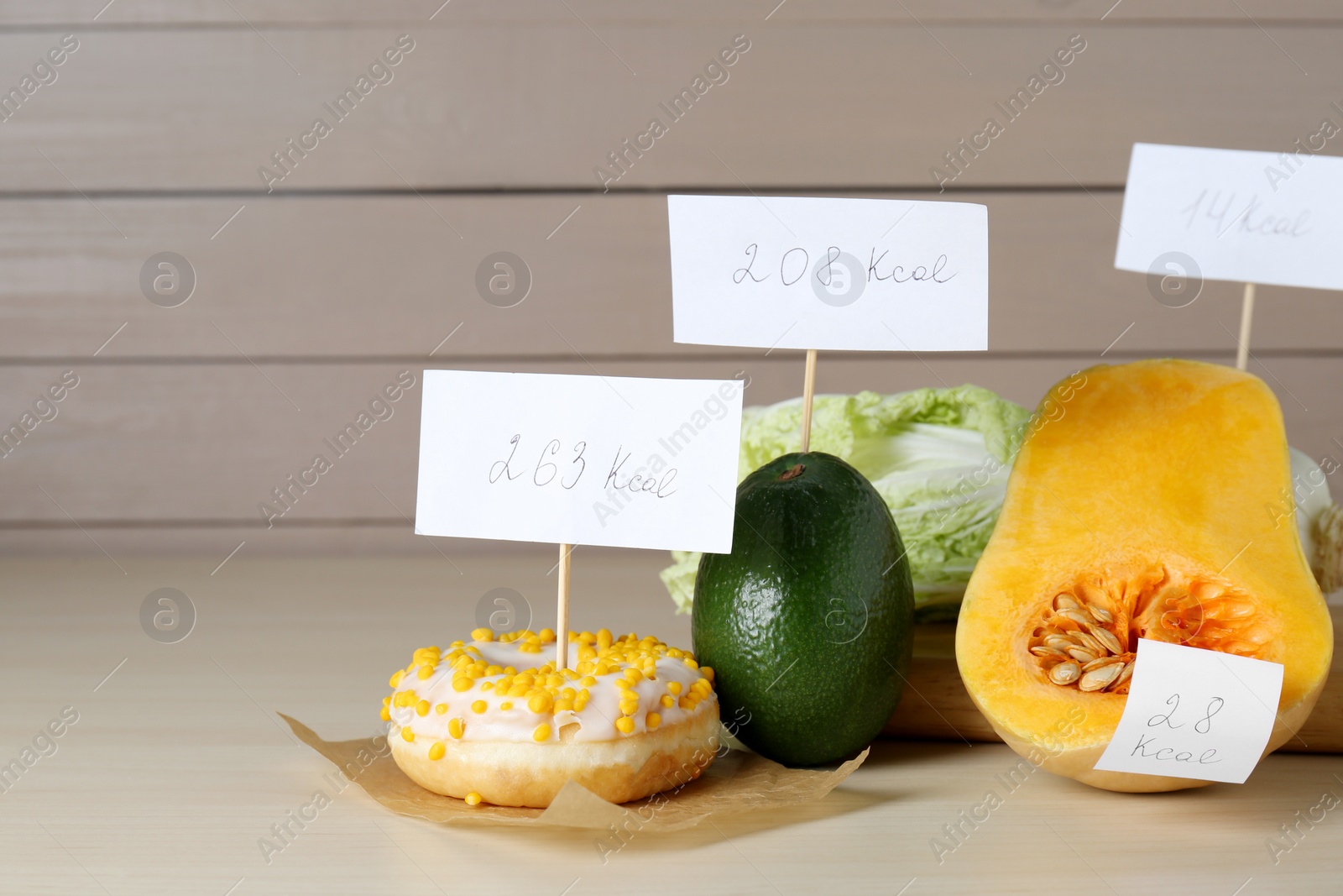 Photo of Food products with calorific value tags on wooden table, space for text. Weight loss concept