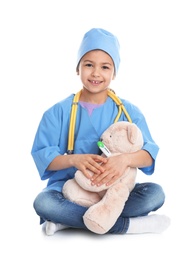 Cute child playing doctor with stuffed toy on white background