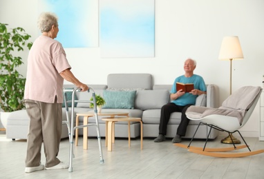 Photo of Elderly woman using walking frame and her husband at home