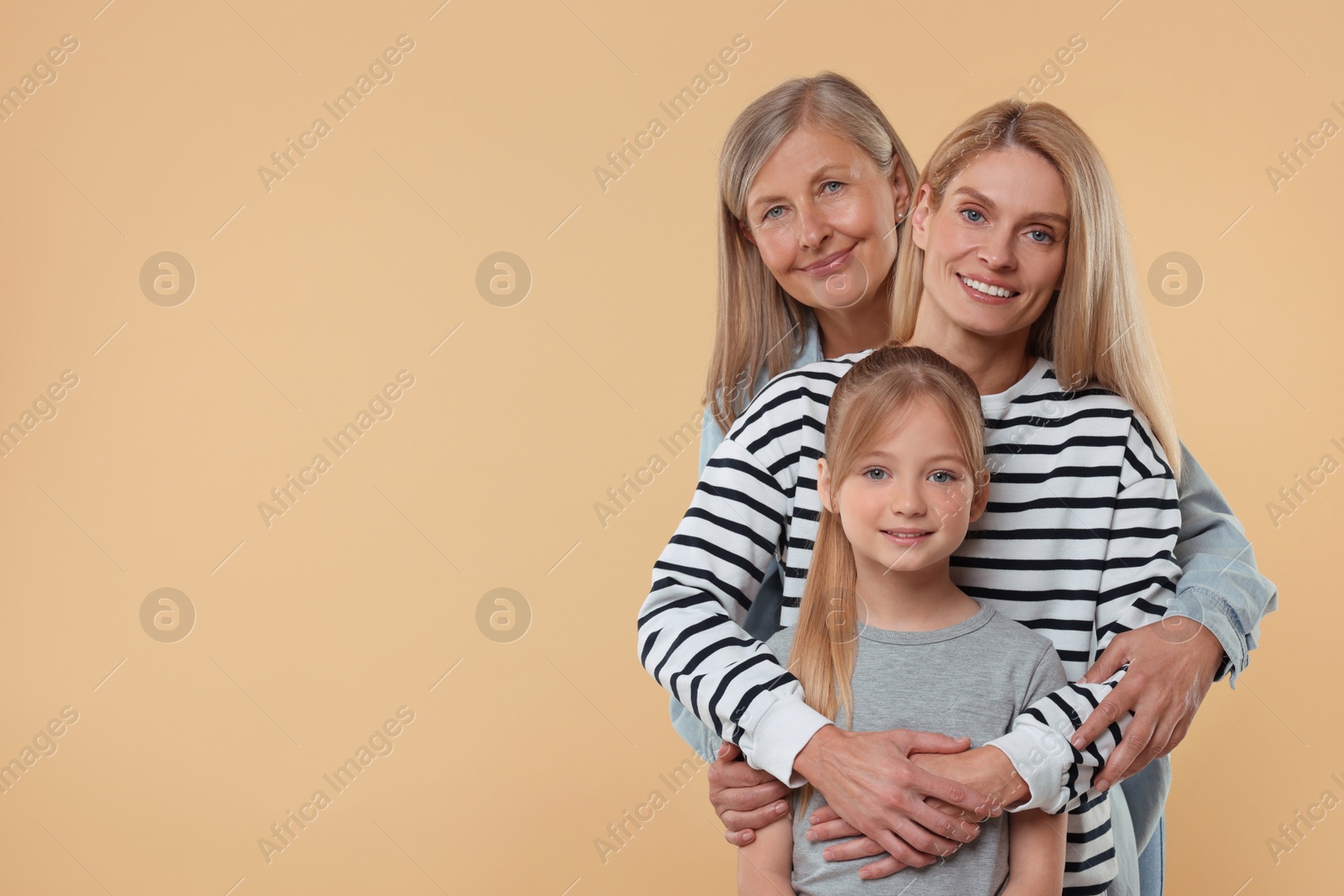 Photo of Three generations. Happy grandmother, her daughter and granddaughter on beige background, space for text