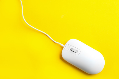 Modern wired optical mouse on yellow background, top view