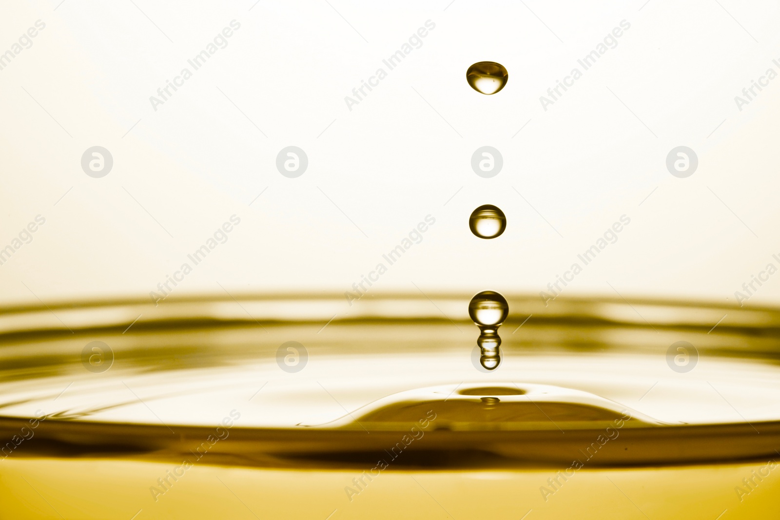 Image of Splash of golden oily liquid with drops on white background, closeup