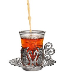 Photo of Pouring traditional Turkish tea into glass in vintage holder on white background