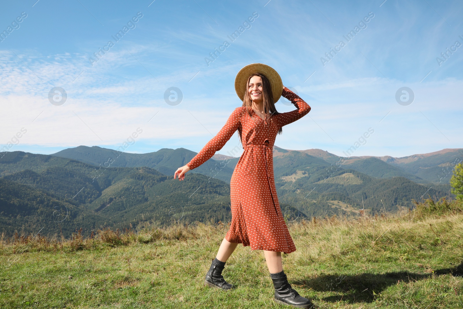 Photo of Young woman with straw hat walking in beautiful mountains on sunny day