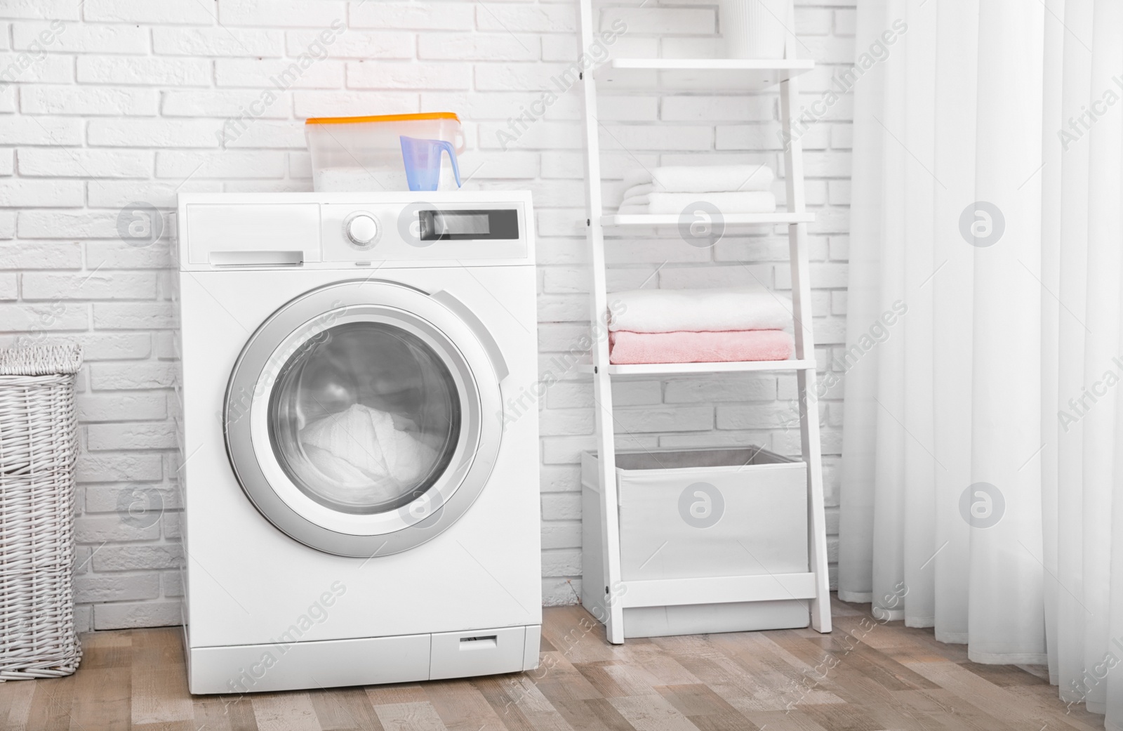 Photo of Modern washing machine near brick wall in laundry room interior