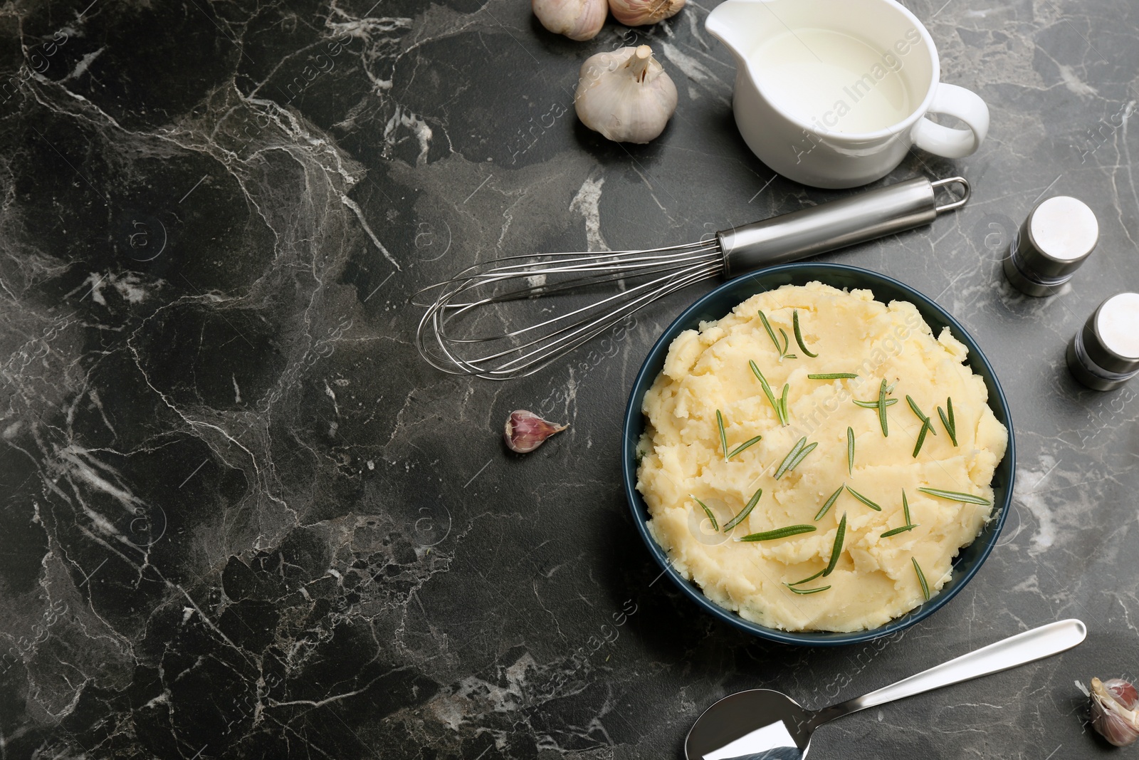 Photo of Flat lay composition with bowl of tasty mashed potato and space for text on dark table