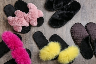 Many different soft slippers on wooden background, flat lay