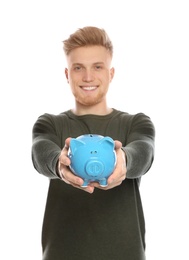 Young man with piggy bank on white background