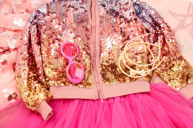 Photo of Stylish carnival costume with sequins, sunglasses and headbands on pink fabric, above view