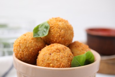 Delicious fried tofu balls with basil in bowl, closeup