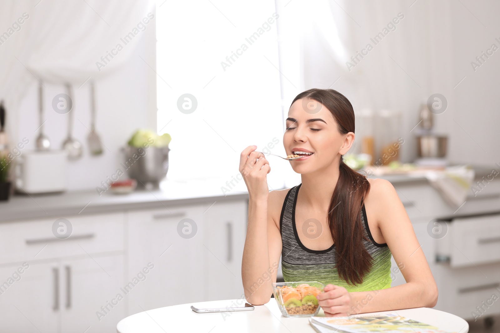 Photo of Young woman in fitness clothes having healthy breakfast at home. Space for text