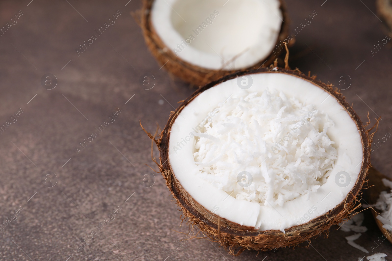 Photo of Coconut pieces in nut shell on brown table, space for text