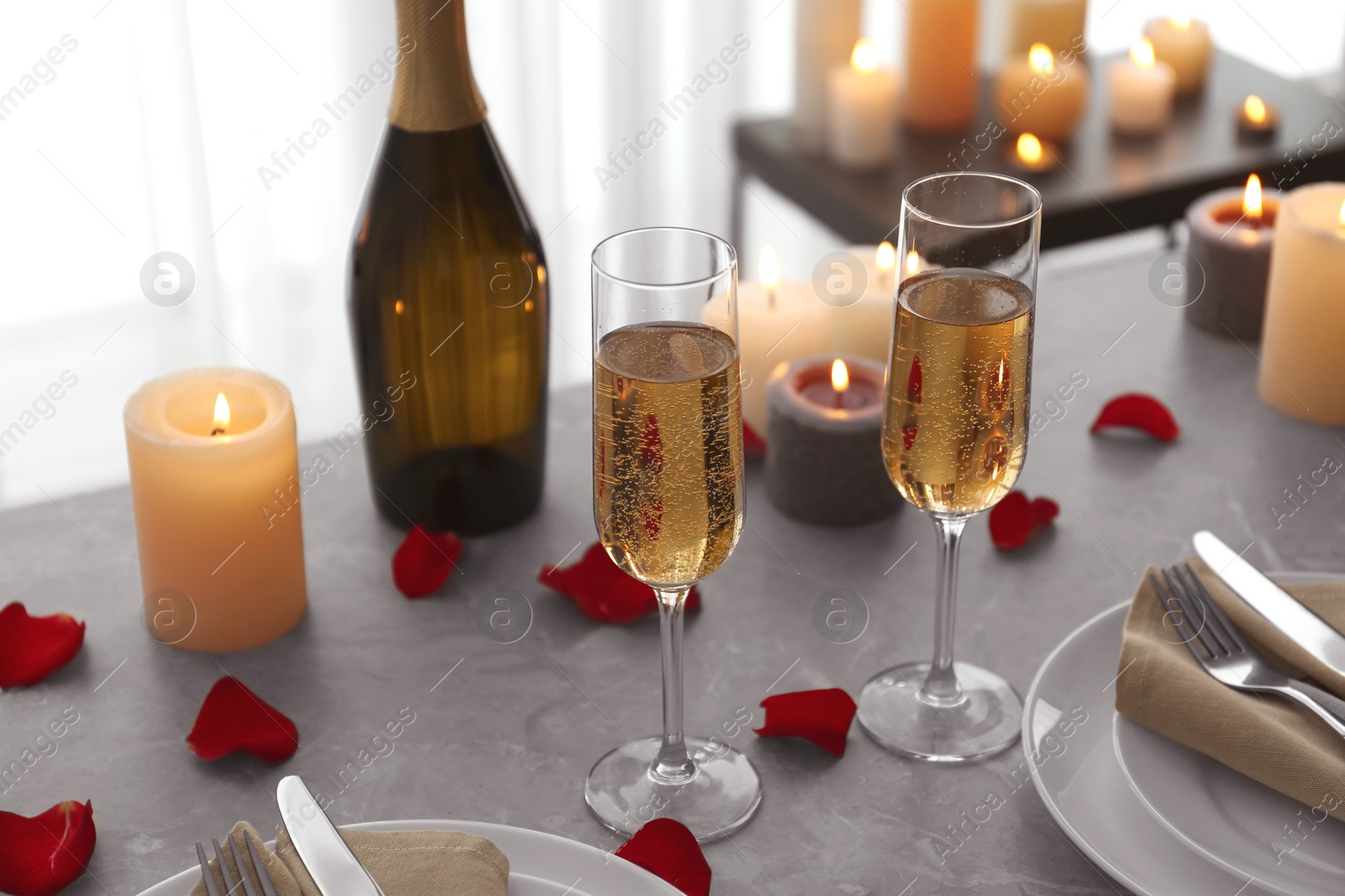 Photo of Romantic table setting with burning candles and rose petals indoors