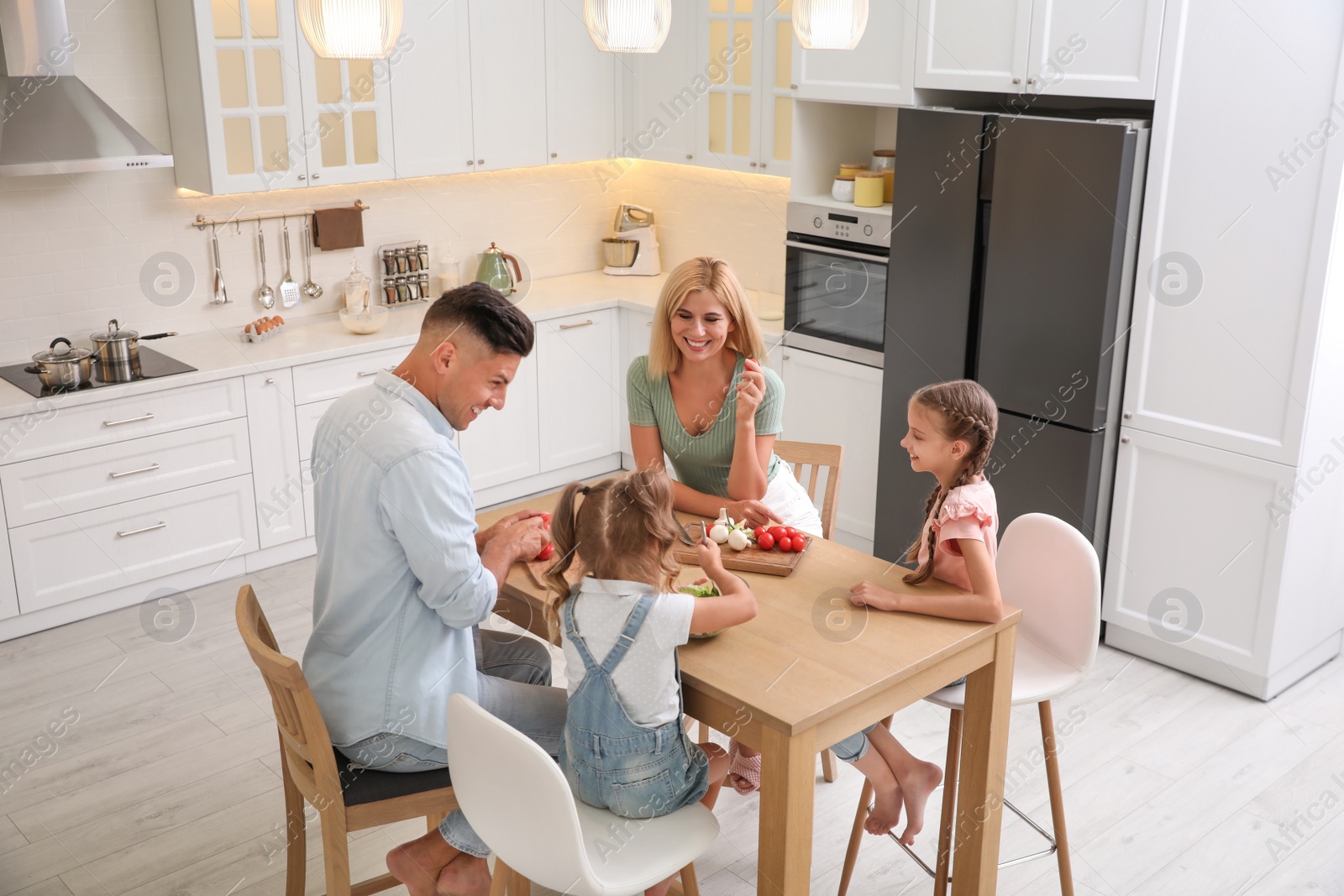 Photo of Happy family cooking together at table in modern kitchen