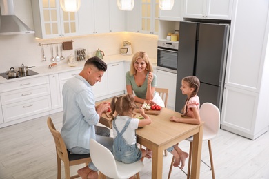 Photo of Happy family cooking together at table in modern kitchen