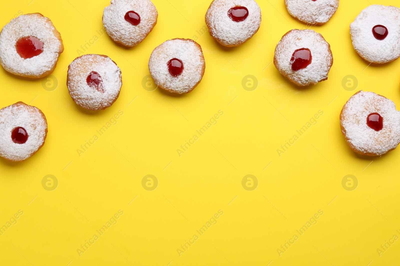 Photo of Hanukkah donuts with jelly and powdered sugar on yellow background, flat lay. Space for text