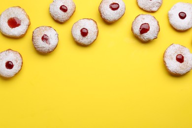 Hanukkah donuts with jelly and powdered sugar on yellow background, flat lay. Space for text