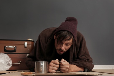 Poor homeless man counting coins on floor