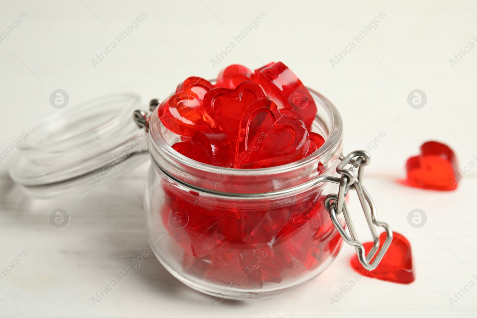 Photo of Sweet heart shaped jelly candies on white wooden table, closeup