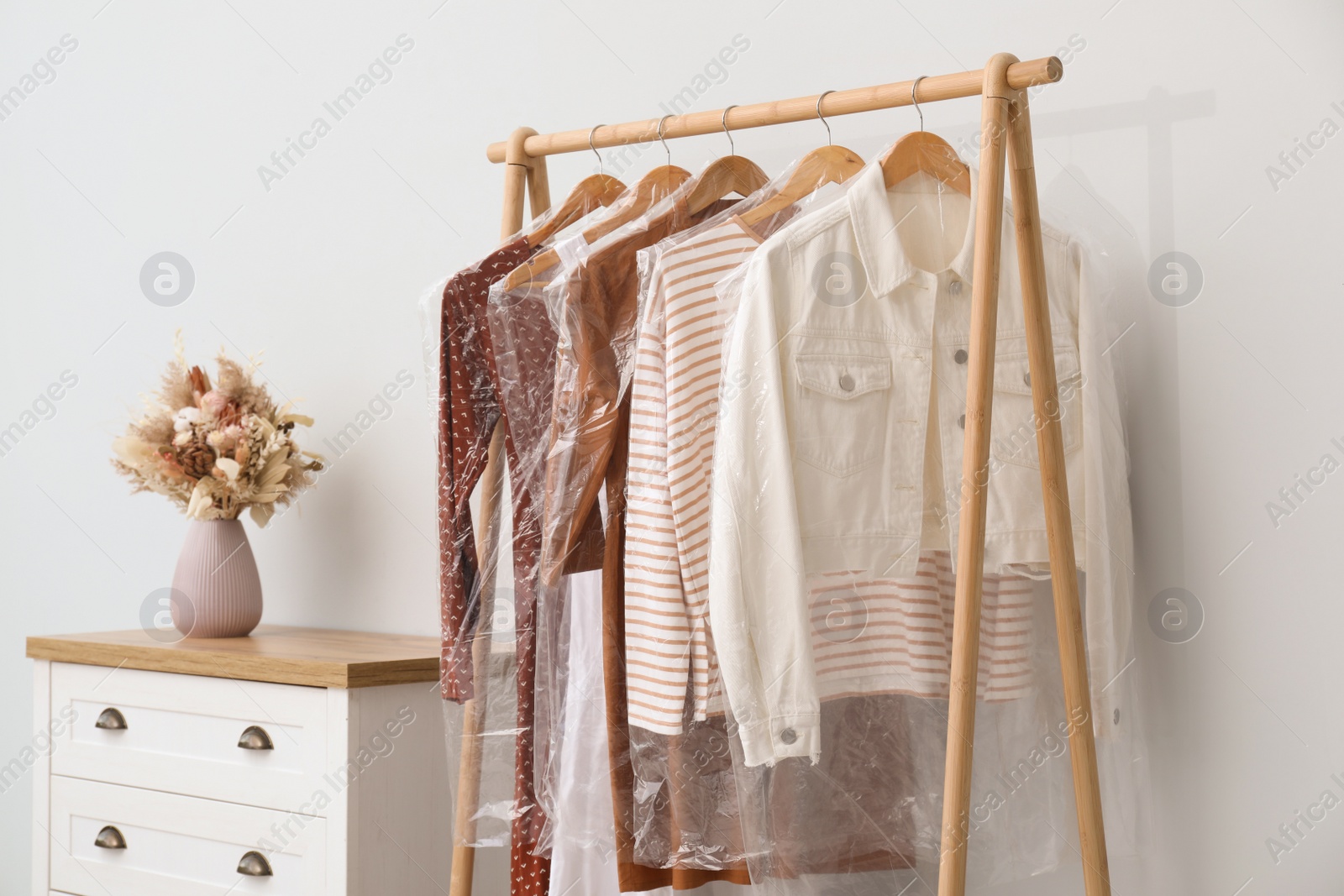 Photo of Rack with clothes in plastic bags indoors