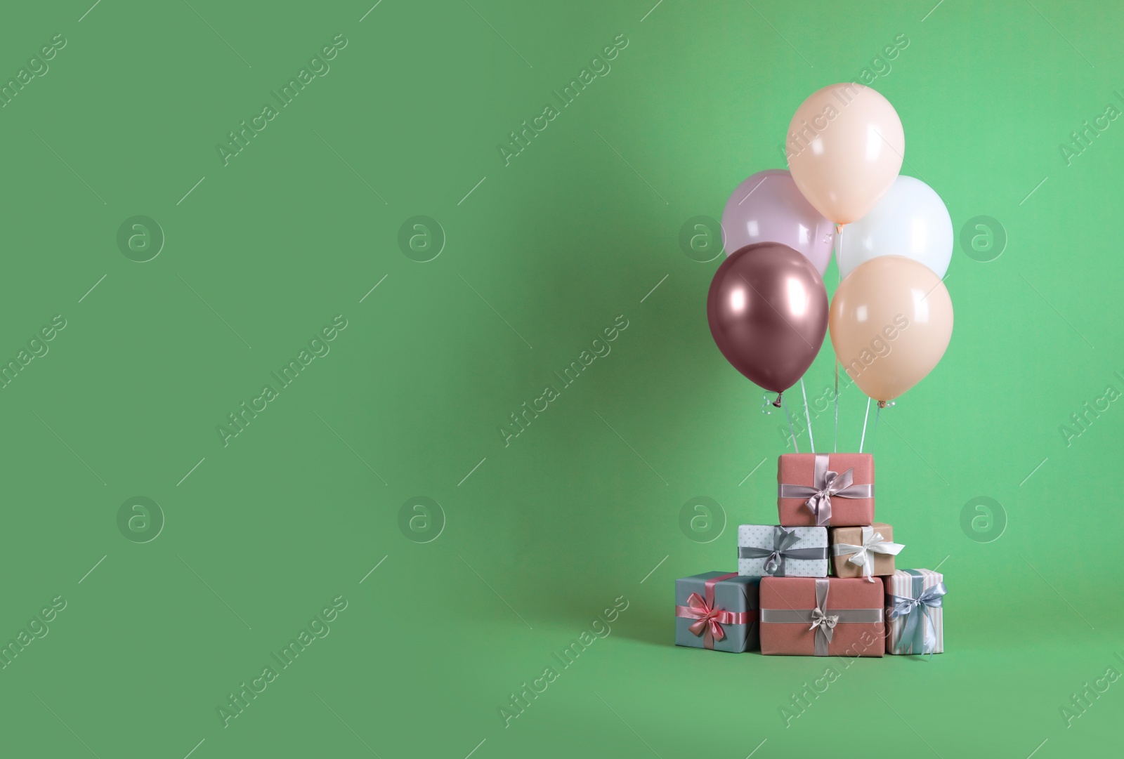 Photo of Bunch of color balloons and beautifully wrapped gift boxes on green background. Space for text