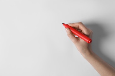 Photo of Woman holding red marker on white background, top view. Space for text