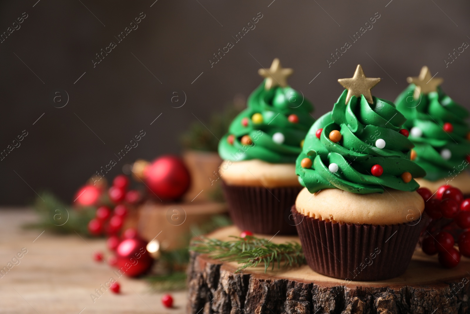 Photo of Christmas tree shaped cupcakes on wooden stand, closeup. Space for text
