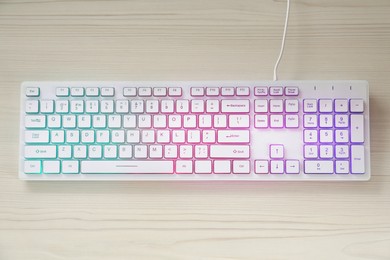 Photo of Modern RGB keyboard on white wooden table, top view