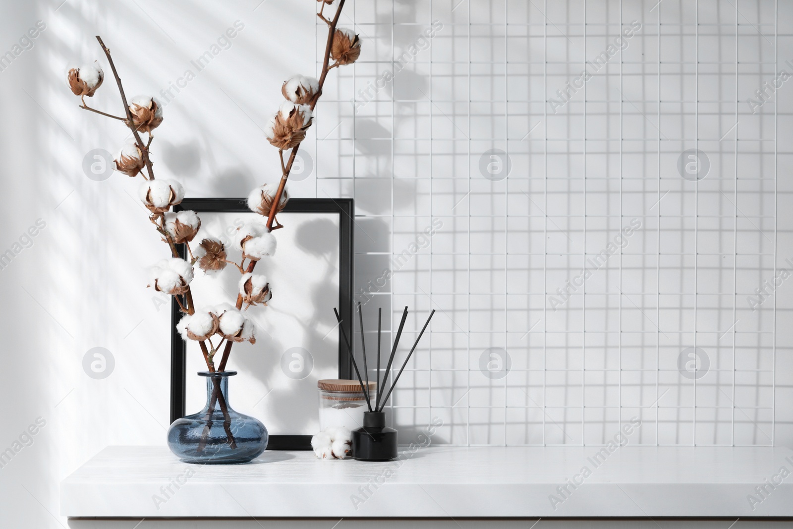 Photo of Reed diffuser, candle and cotton branches with fluffy flowers on white wooden table indoors. Space for text