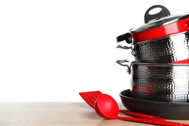 Stack of clean cookware and utensils on table against white background, space for text