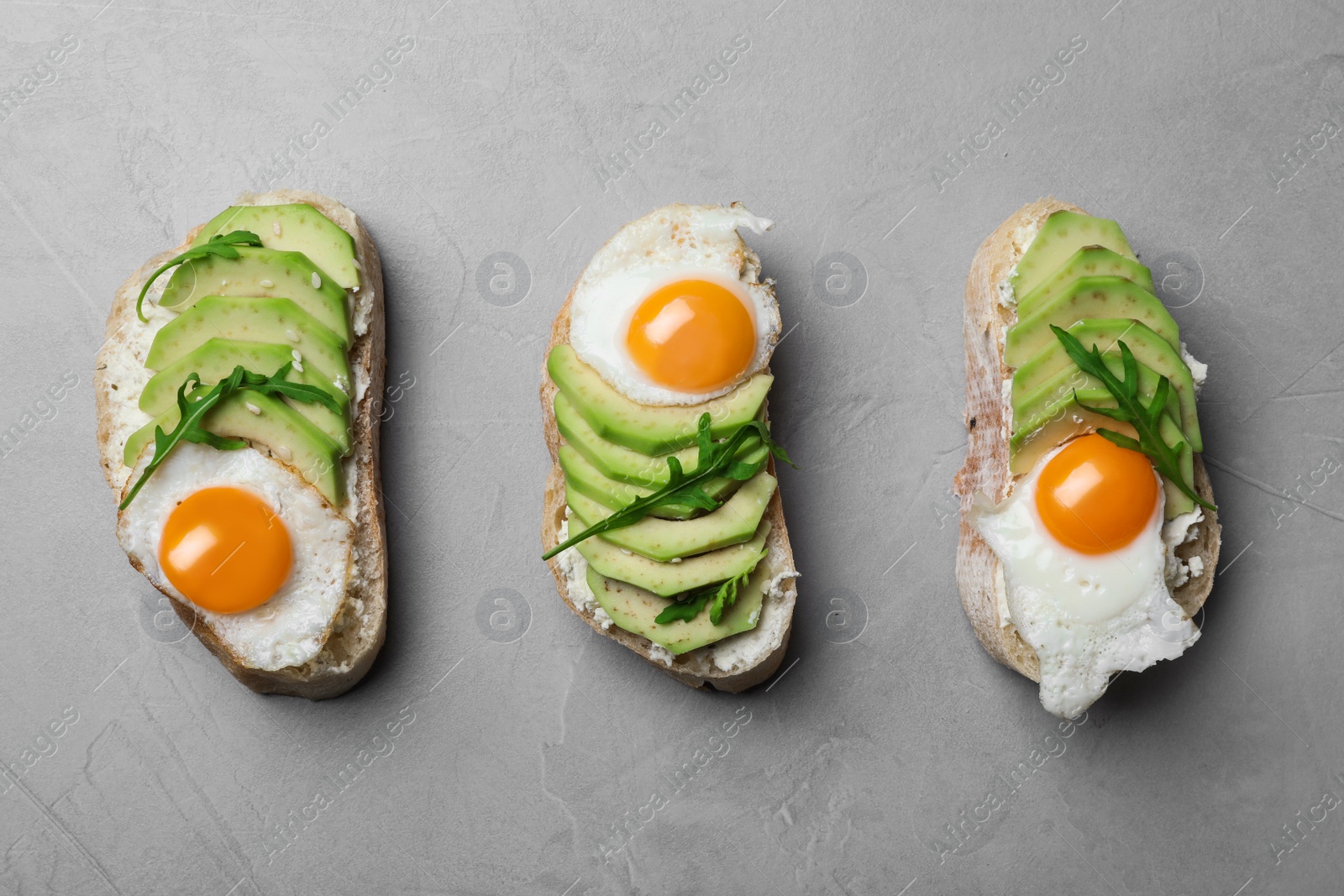 Photo of Delicious avocado sandwiches on grey table, flat lay