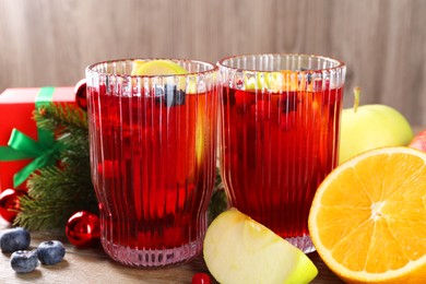 Photo of Aromatic Sangria drink in glasses, ingredients and Christmas decor on table