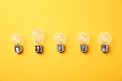 Photo of Vintage and modern incandescent lamp bulbs on yellow background, flat lay