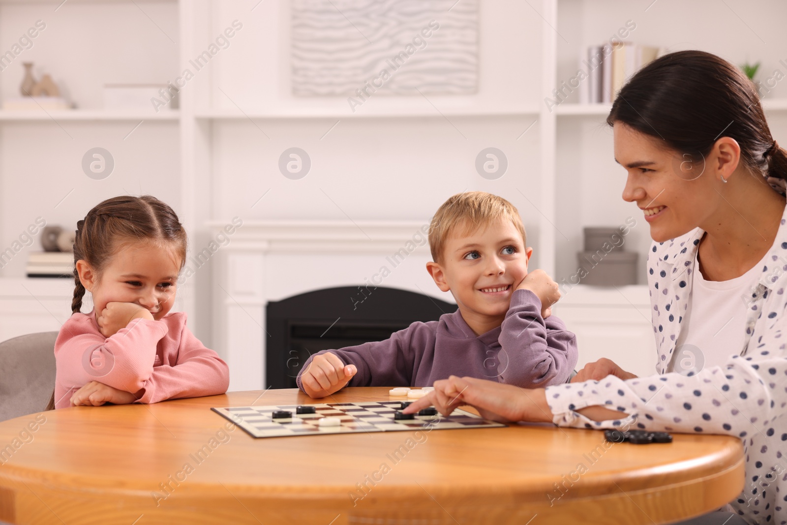 Photo of Family playing checkers at wooden table in room