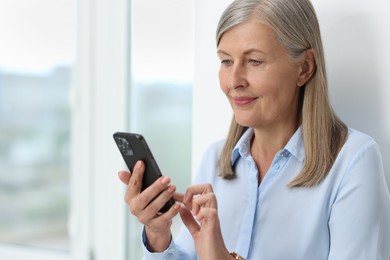 Senior woman using mobile phone at home