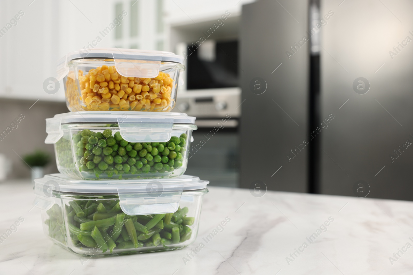 Photo of Glass containers with different fresh products on white marble table in kitchen, space for text. Food storage