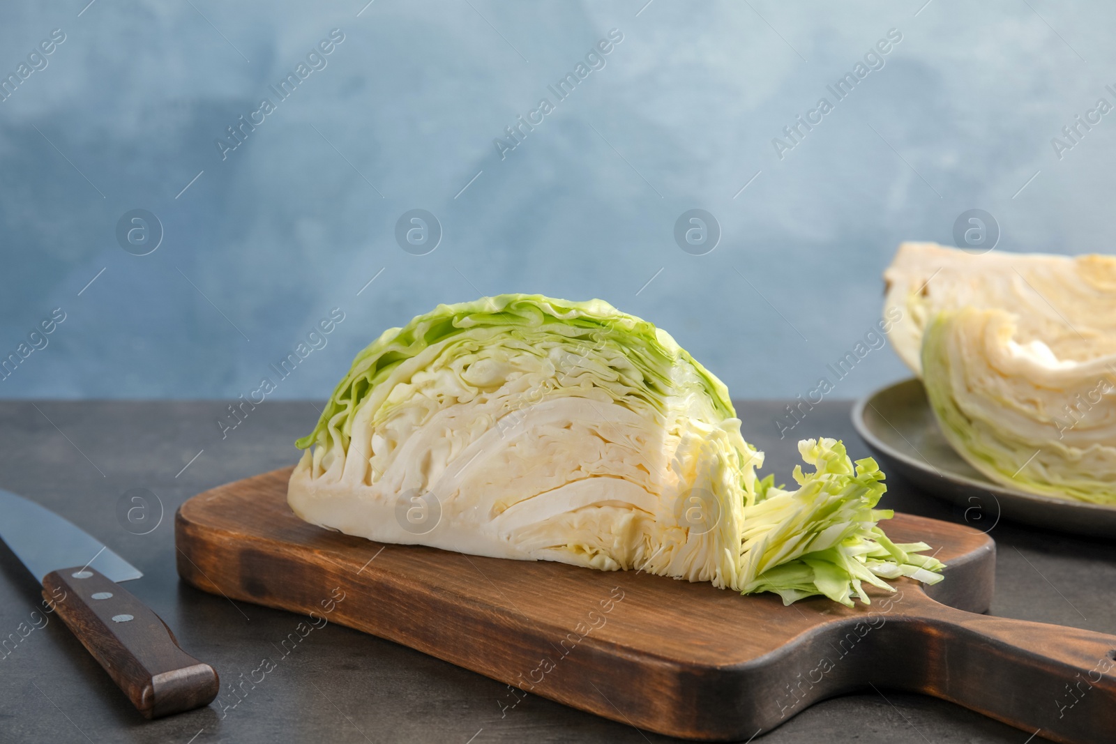 Photo of Wooden board with cut cabbage on table