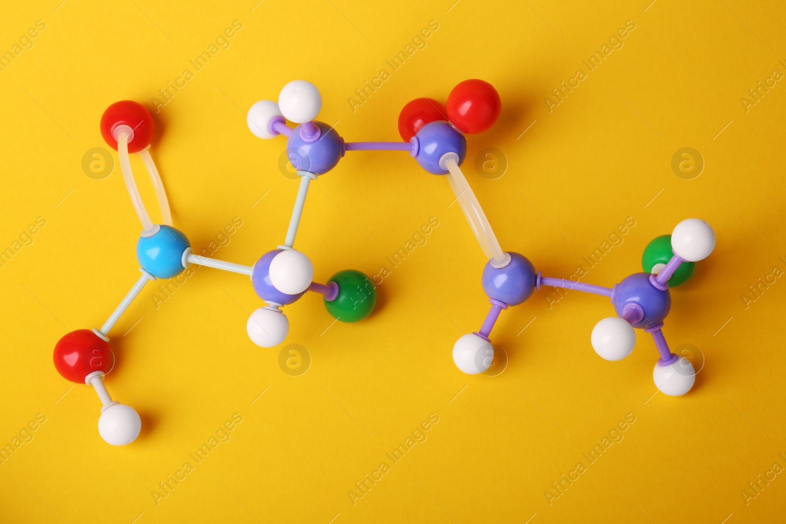 Photo of Structure of molecule on yellow background, top view. Chemical model