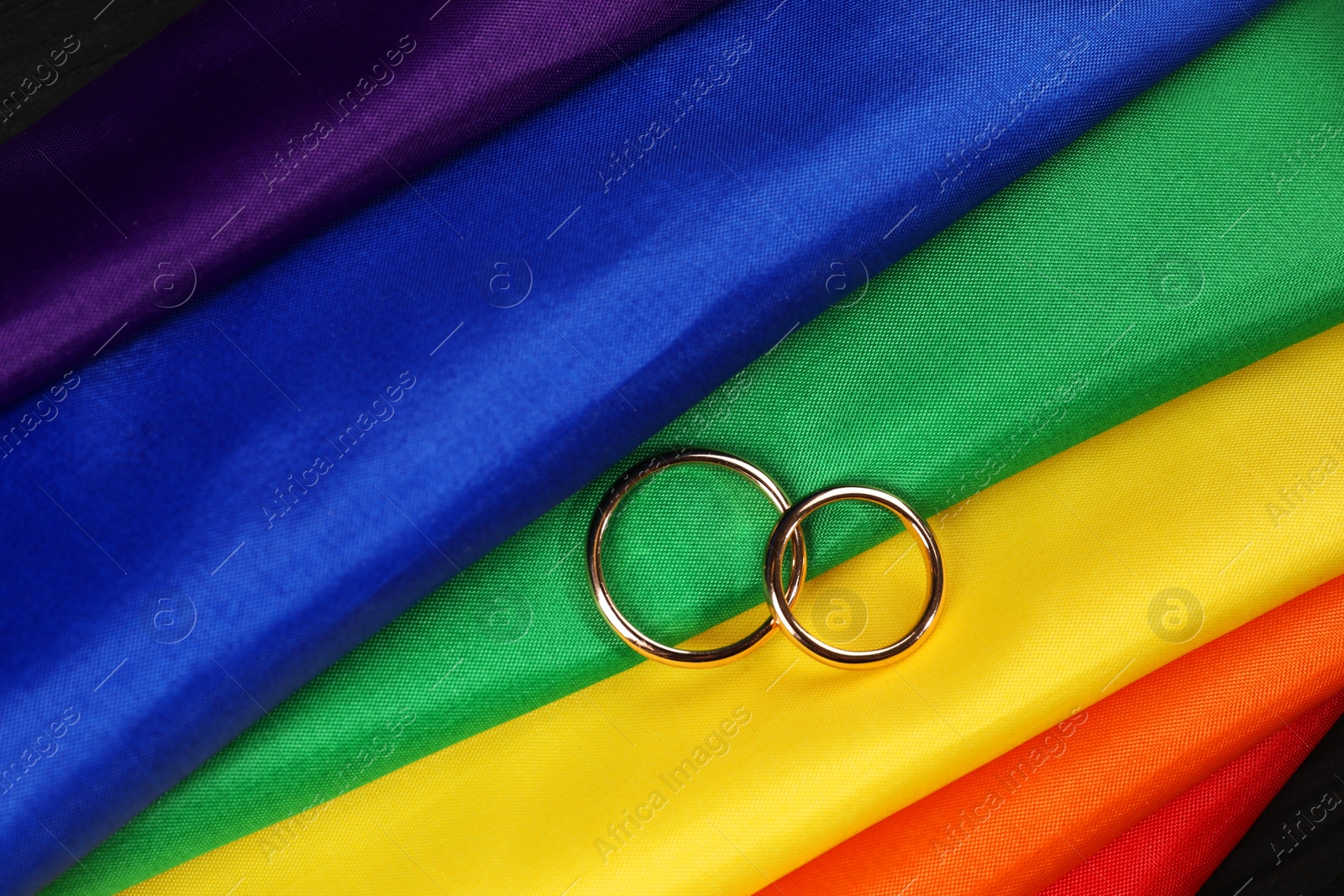 Photo of Wedding rings on rainbow LGBT flag, top view