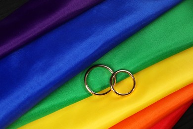 Wedding rings on rainbow LGBT flag, top view