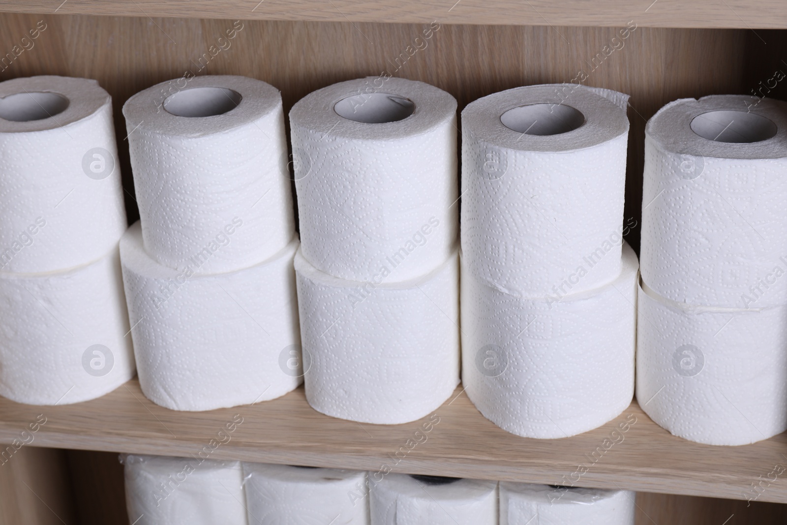 Photo of Stacked toilet paper rolls on wooden shelf