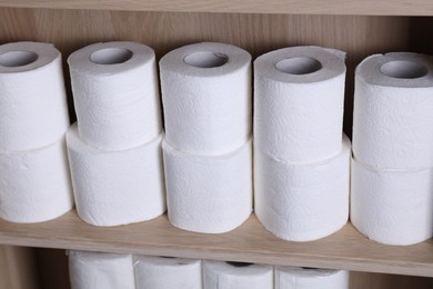 Stacked toilet paper rolls on wooden shelf