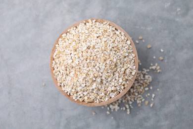 Photo of Raw barley groats in bowl on grey table, top view